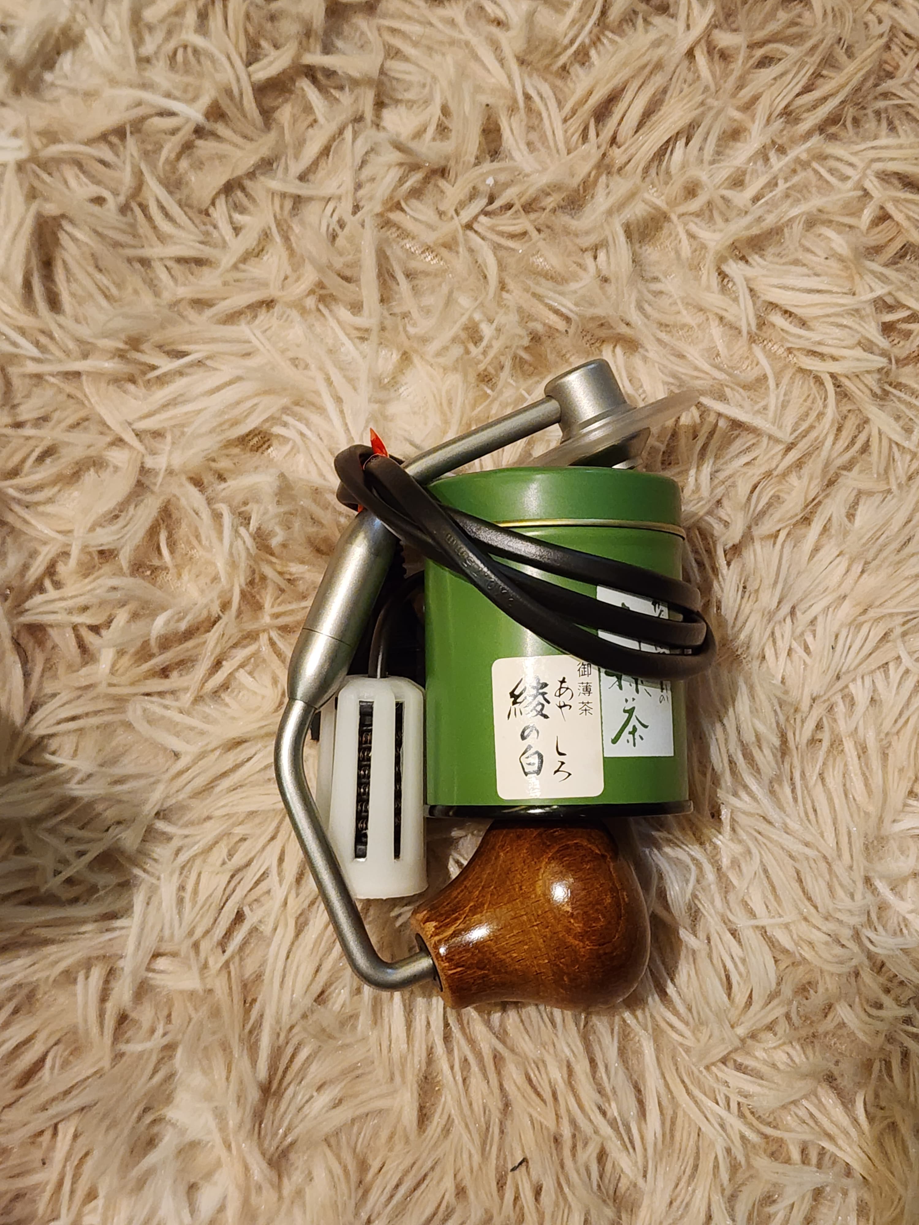 Tea can, immersion heater, tea infuser, and grinder handle bundled together before going into the 1Zpresso sleeve.